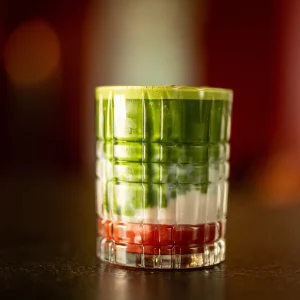 Dreifarbig geschichteter Matcha-Drink, im Hintergrund unscharfe Lichter des charc Café in Nürnberg